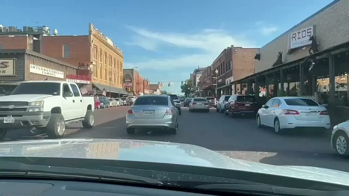 A historic brick storefront strip in the Fort Worth Stockyards, with a mounted buffalo head on a wall and wooden porch awnings