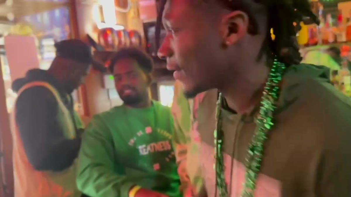 Uche and two friends wearing green St. Patrick's Day beads at a bar in Ann Arbor