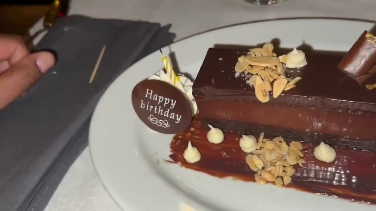 A plated chocolate dessert with a round "Happy Birthday" chocolate disc and toasted almonds